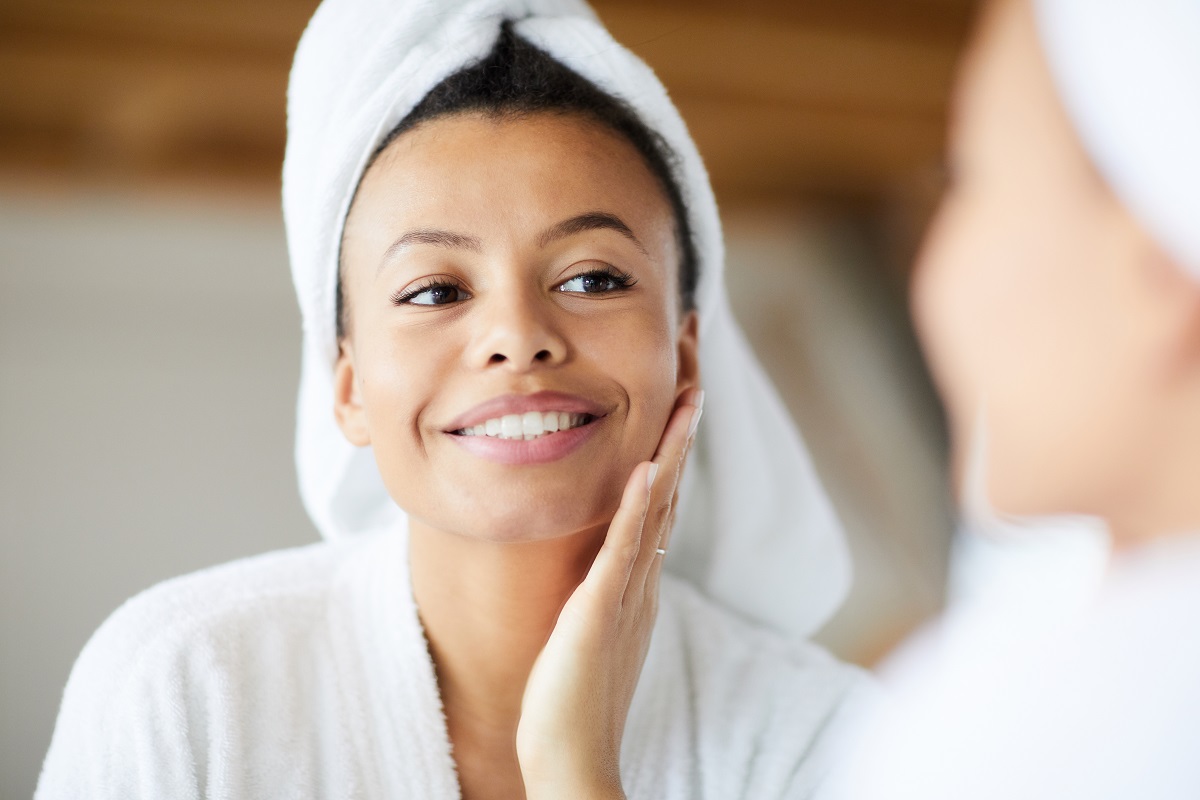 woman looking in the mirror - moringa oil skin benefits